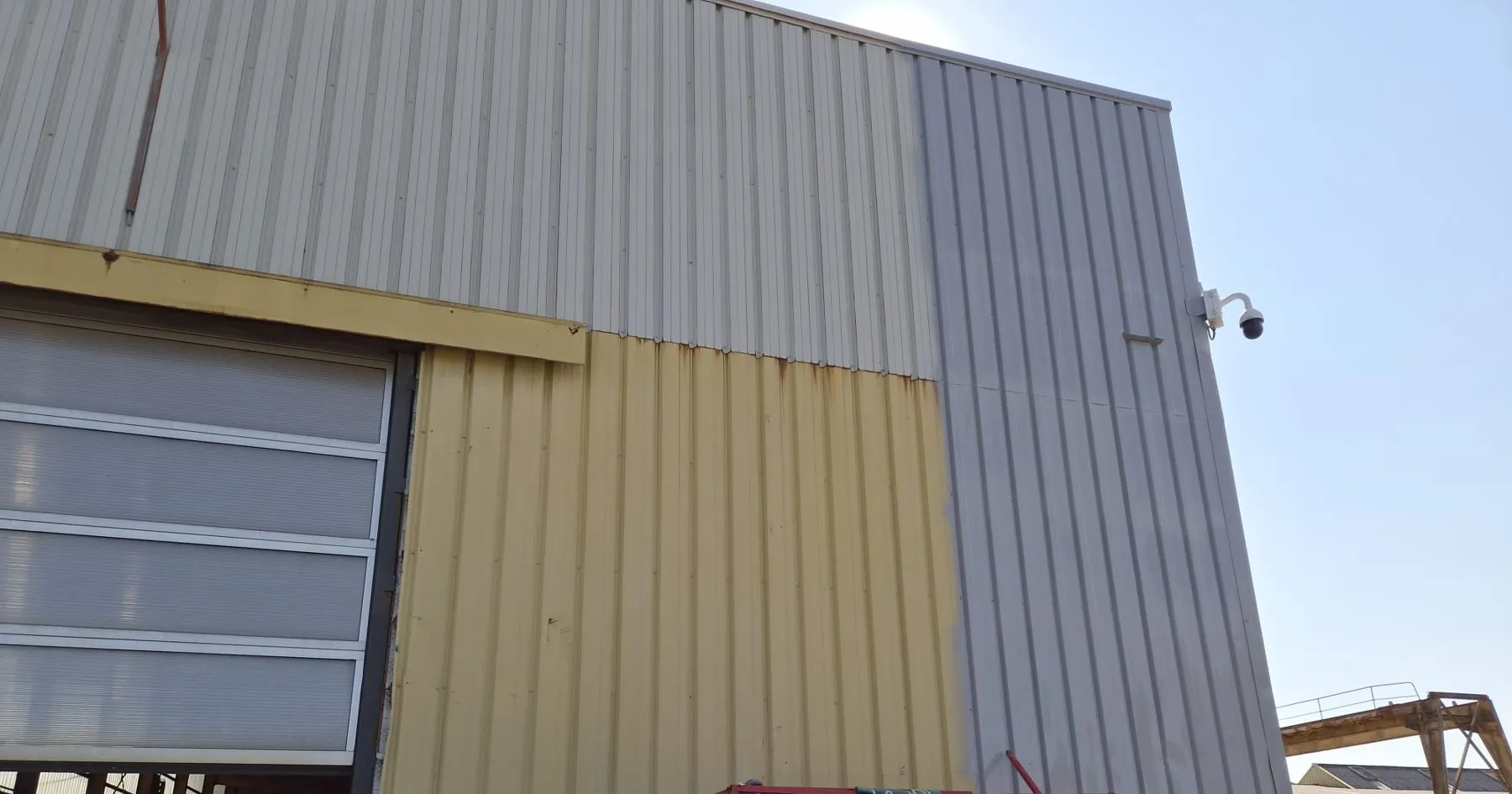Détail du bardage métallique, un panneau gris à côté d'un panneau jaune