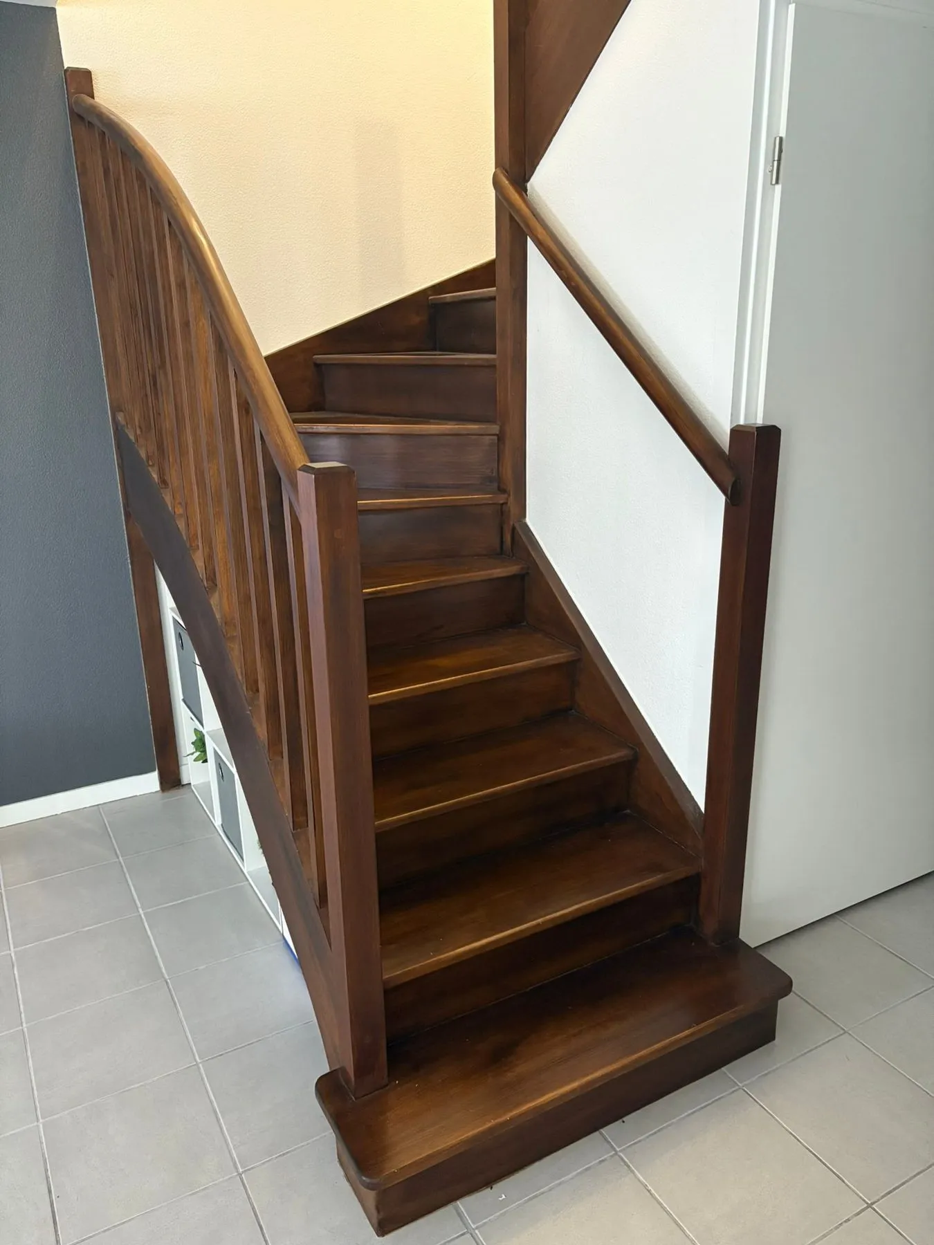 Escalier tournant en bois foncé avant les travaux de peinture