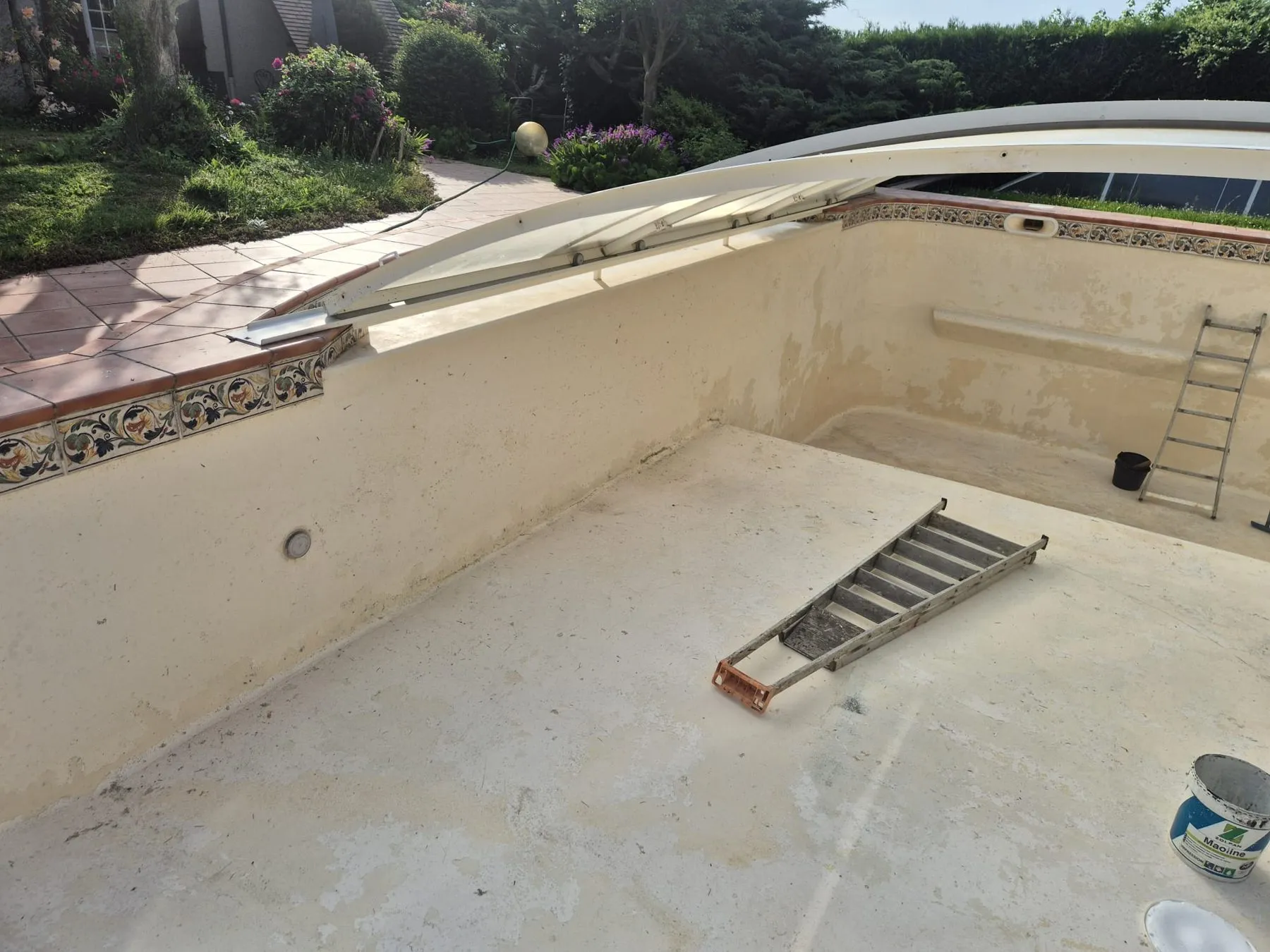 Bassin de piscine vidé avant les travaux, avec son ancien revêtement dégradé