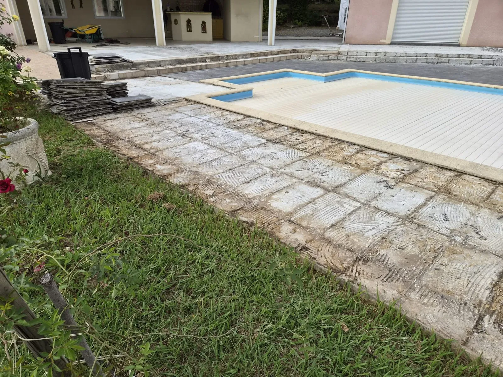 Terrasse dont l'ancien carrelage a été déposé, côté pelouse, près de la piscine