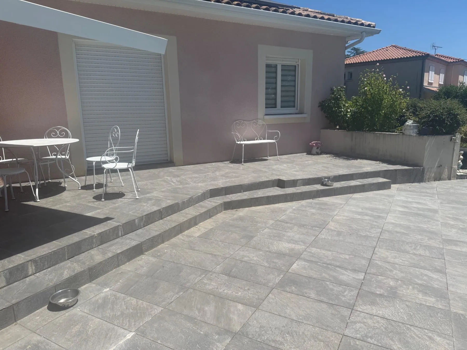 Terrasse carrelée en gris devant une maison, avec un emmarchement