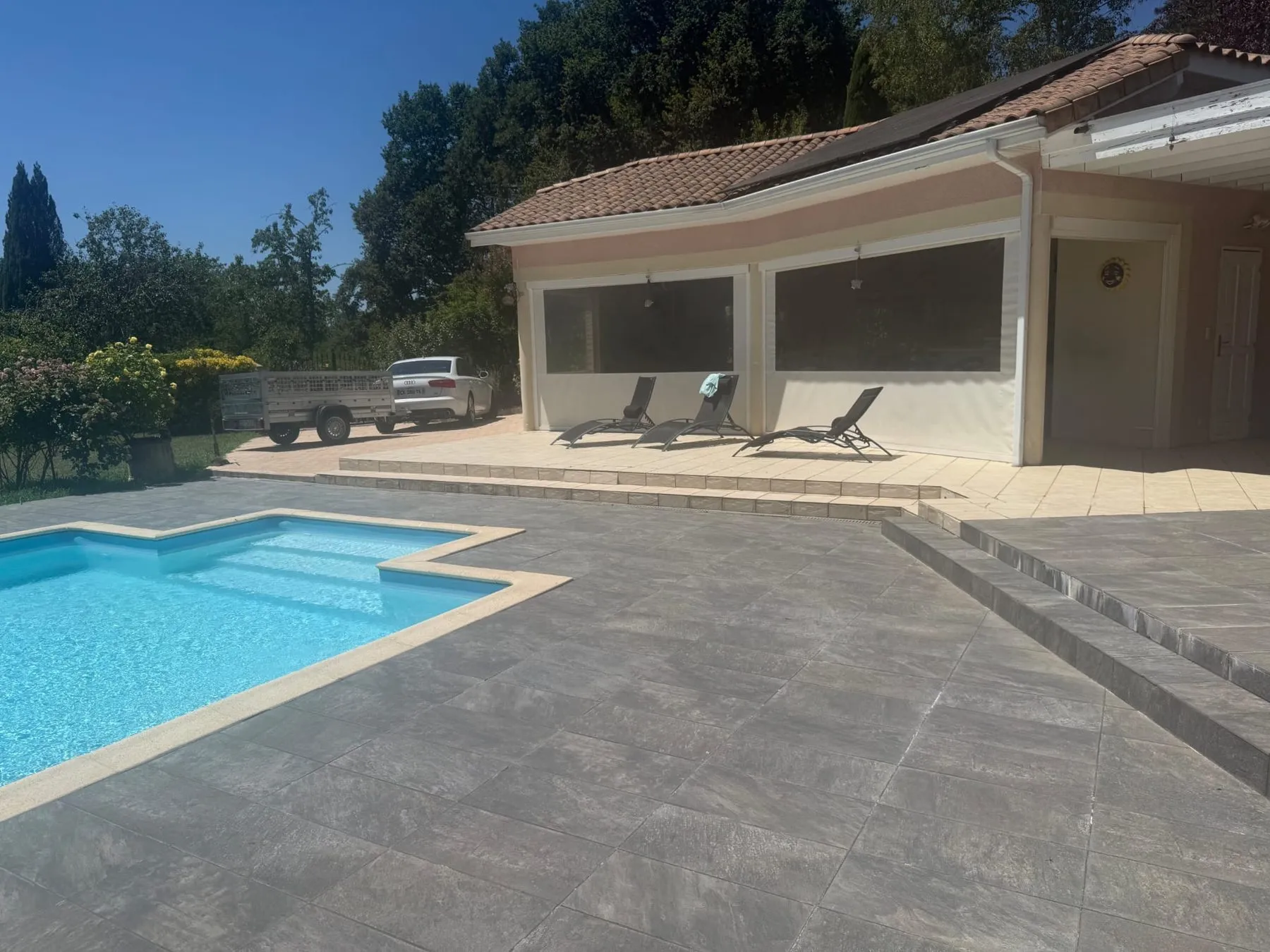 Terrasse autour d'une piscine entièrement recouverte d'un carrelage gris